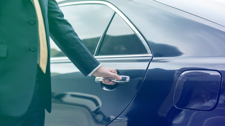 stock image of a man in a suit opening a limo door