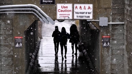 Students walk under the O-Train tracks as snow falls on Carleton University, in Ottawa on Tuesday, April 17, 2018. Endless Winter 20180417