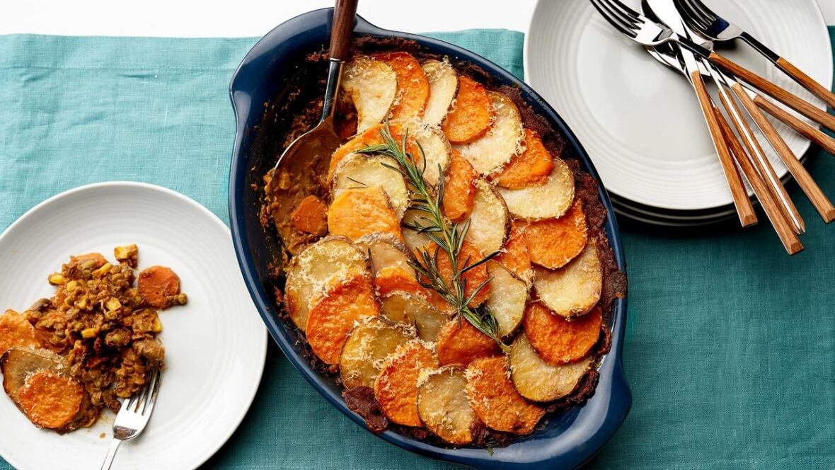 Top down shot of a casserole dish with a lentil shepherds pie. The top is covered with slices of potato and sweet potato. 
