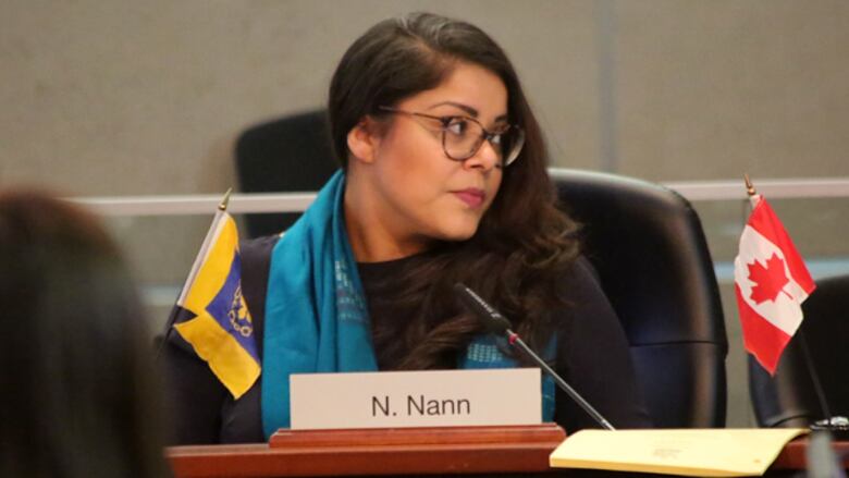 A woman sits in council chambers.