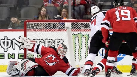 New Jersey Devils goaltender Cory Schneider falls to the ice while reaching to defend against Ottawa Senators left wing Brady Tkachuk (7) during the second period. senators-devils