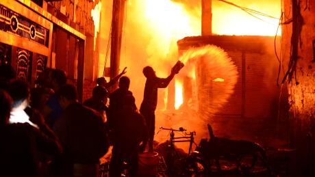 In this Wednesday, Feb. 20, 2019, file photo, firefighters and local people help douse a fire in Dhaka, Bangladesh. A devastating fire raced through at least five buildings in an old part of Bangladesh's capital and killed scores of people. Bangladesh fire Dhaka