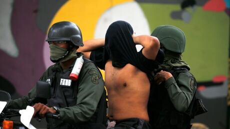 Venezuelan Bolivarian National Guard soldiers detain an anti-government protester, whose face they covered, after a rally demanding the resignation of President Nicolas Maduro in Caracas, Venezuela, Wednesday, Jan. 23, 2019. APTOPIX Venezuela Political Crisis