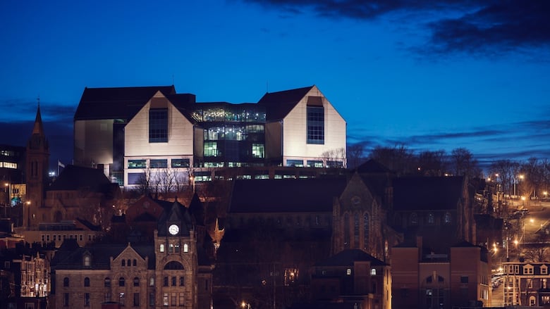 Image of a box-shaped building lit up against blue sky.