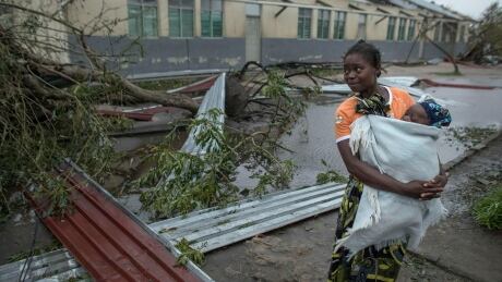 A woman makes her way to a school building being used as an emergency shelter for some 300 local people who are unable to return to their homes following cyclone force winds and heavy rain in the coastal city of Beira, Mozambique, Sunday March 17, 2019. More than 1,000 people are feared dead in Mozambique four days after a cyclone slammed into the southern African country destroying vulnerable residential areas. Mozambique Cyclone
