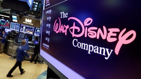 The Walt Disney Co. logo appears on a screen above the floor of the New York Stock Exchange. Film Fox Disney