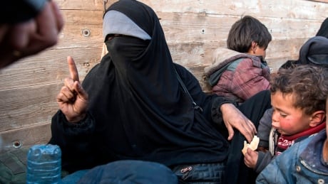 A woman (grey veil) claiming to be a 31 years old French citizen from Lyon, France, who fled the last Islamic State group's tiny pocket in Syria sits in the back of a truck, near Baghuz, eastern Syria, on February 11, 2019. - Two French women who fled the last IS pocket told AFP on February 11 more foreigners were trapped inside, barred from leaving by Iraqi jihadists. 1097912722