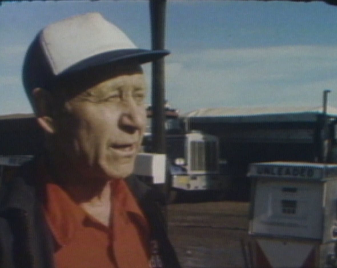 Man waring trucker hat and standing next to gas pump