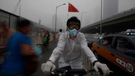 epa03764692 A man wears a mask on his bicycle as smog engulfs the city of Beijing, China, 28 June 2013. Thick smog envelops the Chinese capital 28 June where air quality is rated as 'hazardous' with a PM2.5 fine-particle pollutants reading of 406 and ozone level of 438 at 9pm, Beijing time according to air pollution readings by monitors installed in the US embassy. EPA/HOW HWEE YOUNG CHINA POLLUTION SMOG