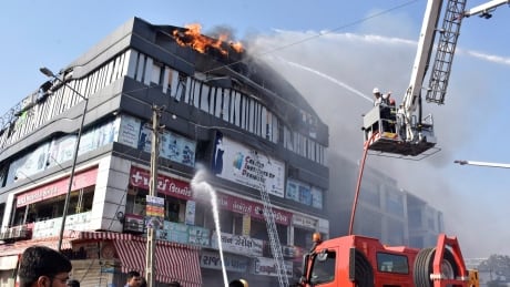Firefighters work to douse flames on a four-storey building in Surat, in the western Indian state of Gujarat on Friday. India Deadly Fire