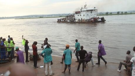 People that have been deported from Congo's capital Brazzaville, seen in background, arrive by river boat, center rear, in Kinshasa, Democratic Republic of Congo, Tuesday, April 29, 2014. Officials say nearly 40,000 Congolese citizens have been deported from neighboring Republic of Congo because they did not have immigration papers. Kinshasa Governor Andre Kimbuta said Tuesday that the biggest wave of deportees had arrived the day before, when 6,000 people crossed the Congo River separating the two countries. (AP Photo/John Bompengo) Congo Mass Deportations