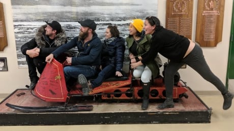 The Jerry Cans and Unreserved's Rosanna Deerchild pose on a snowmobile at Inuksuk High School in Iqaluit, Nunavut. Jerry Cans and Rosanna