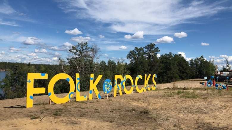 Letters stood up on a beach reading Folk on the Rocks.
