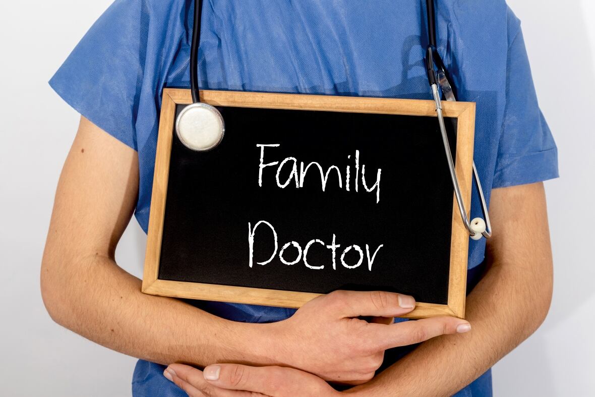 Doctor holding a Family Doctor sign on a chalkboard.