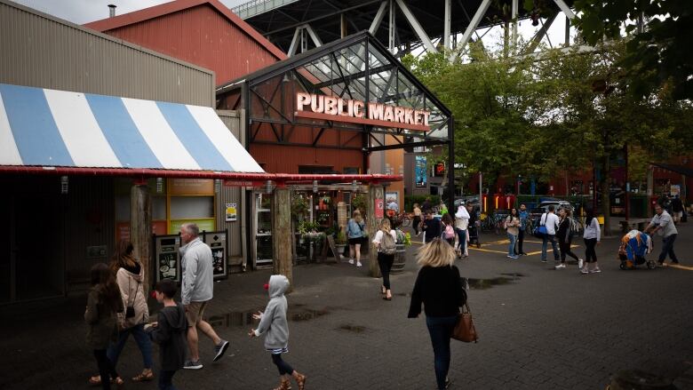 A group of people mill about at Granville Island Public Market.