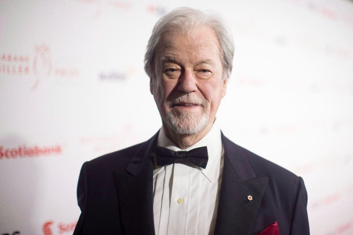 An elderly man with a tux stares into the camera