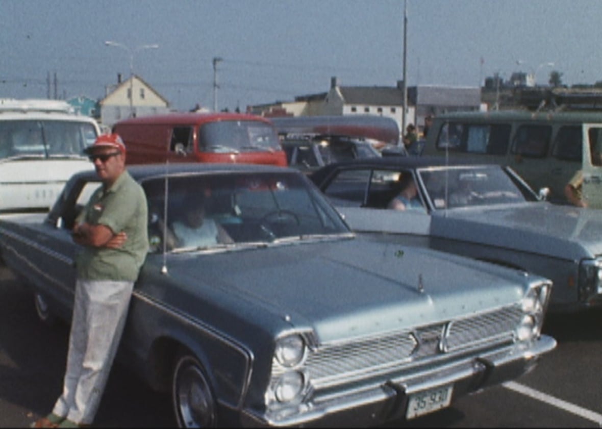 Person leaning against a blue 1960s car