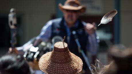 An eagle feather attached to a hat worn by Kwikwetlem First Nation Chief Ed Hall blows in the wind as Chief Joe Alphonse, back, Tribal Chair of the Tsilhqot'in National Government, speaks during a ceremony to commemorate the wrongful trial and hanging of Chief Ahan, in New Westminster, B.C., on Thursday July 18, 2019. Chief Remembered 20190718
