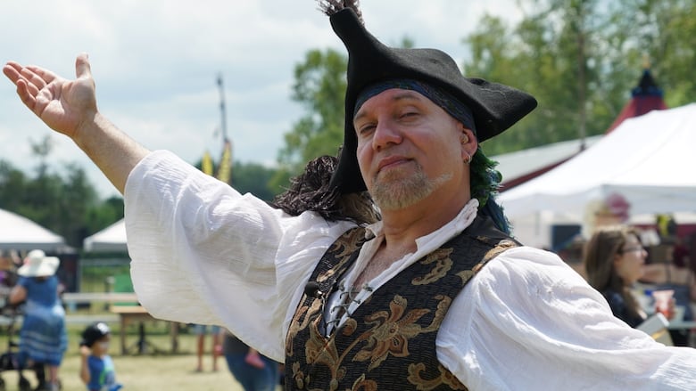 A man dressed as a pirate with a hat poses for a photo