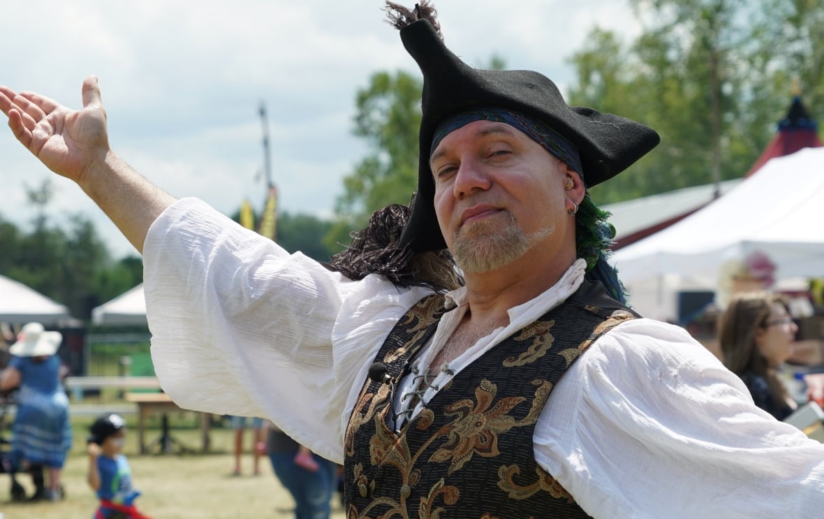A man dressed as a pirate with a hat poses for a photo