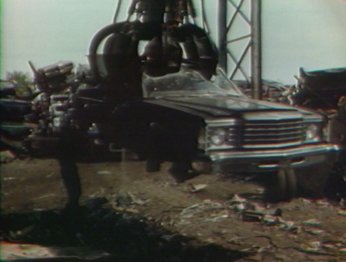 Car being lifted up by large claw