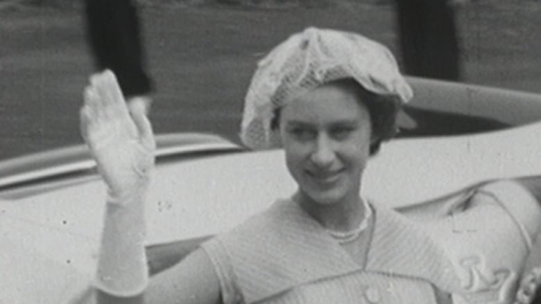 woman waving from back seat of open-top car