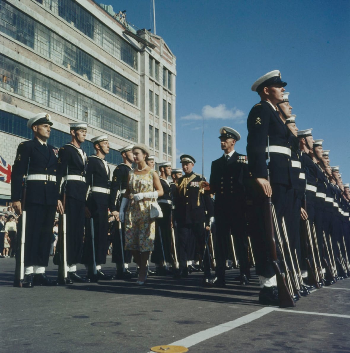 woman walking between two rows of uniformed men