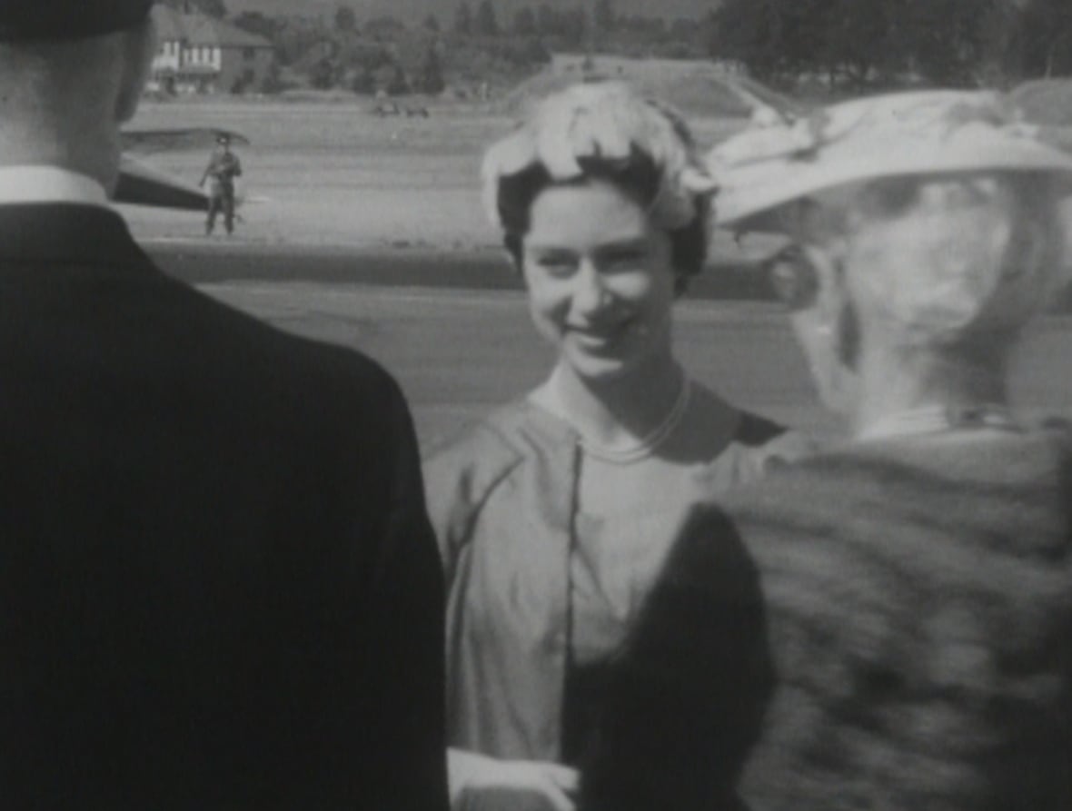 smiling woman facing camera positioned behind two others
