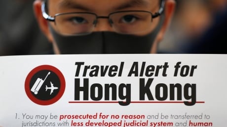 A protester holds up a banner warning of the dangers of traveling to Hong Kong at the airport in Hong Kong on Friday, Aug. 9, 2019. Pro-democracy protesters held a demonstration at Hong Kong's airport Friday even as the city sought to reassure visitors to the city after several countries issued travel safety warnings related to the increasing levels of violence surrounding the two-month-old protest movement. (AP Photo/Vincent Thian) Hong Kong Protests