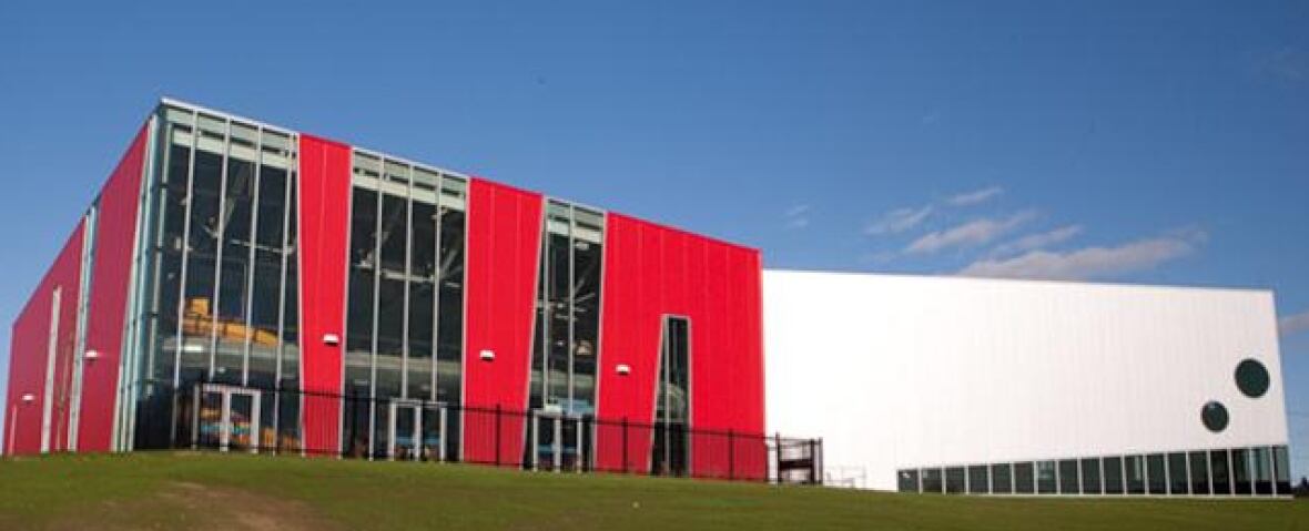 A building clad with bright red material around tall, narrow windows on one side and white cladding on the rest.