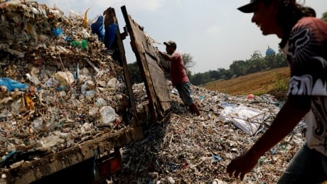 Workers prepare to unload waste, brought from a paper factory, next to paddy fields at Bangun village in Mojokerto, East Java province, Indonesia, August 1, 2019. ASIA-WASTE/INDONESIA-FARMERS