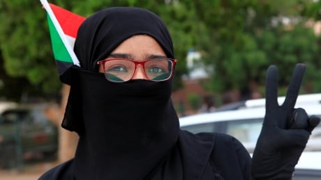 A Sudanese woman waves their national flag and flashes a victory sign during celebrations of the signing of the Sudan's power sharing deal, that paves the way for a transitional government, and eventually elections, following the overthrow of long-time leader Omar al-Bashir in Khartoum, Sudan, Aug. 17, 2019. SUDAN-POLITICS/