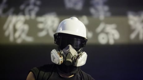 An anti-extradition bill protester stands in front of graffiti outside the People's Liberation Army (PLA) headquarters during a rally to demand democracy and political reforms in Hong Kong, China, August 18, 2019. REUTERS/Thomas Peter - RC1DDBA63D00 HONGKONG-PROTESTS/