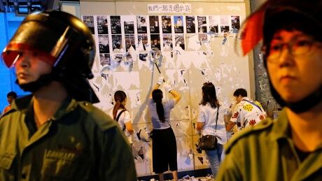 Riot police are seen in front of pro-China supporters as they pull down "Lennon Walls" of anti-government posters and memo notes outside Yuen Long MTR station in Hong Kong, China September 21, 2019. HONGKONG-PROTESTS/