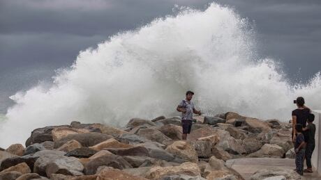 A tourist poses Friday in front of breaking waves before the expected arrival of Hurricane Lorena in Los Cabos, Mexico. The storm has since been downgraded and largely missed the resort area. Mexico Tropical Weather