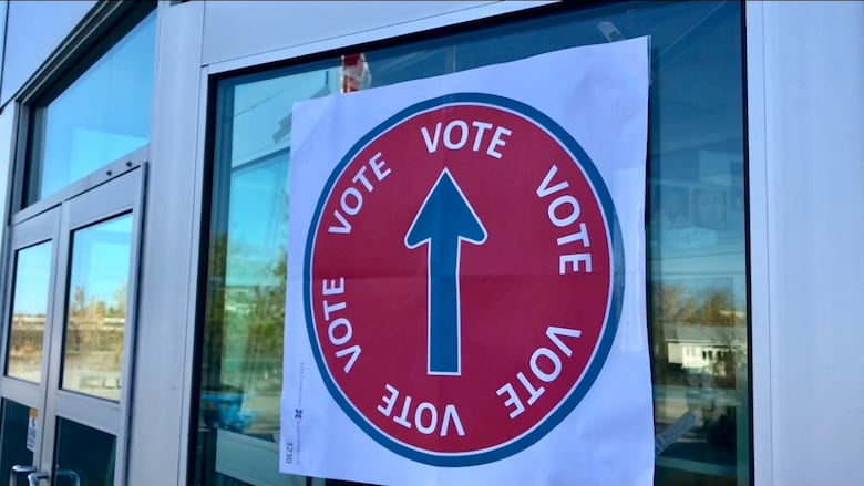 A sign that reads "vote" with an arrow posted to a door.
