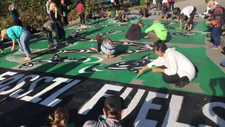 Dozens of activists with Greenpeace Canada paint a mural on Bayview Drive at the entrance to the Trans Mountain pipeline Westridge Marine Terminal on Saturday, Oct. 5, 2019. Greenpeace Canada Westridge Terminal protest mural