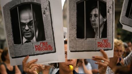 A woman holds placards depicting pictures of jailed Catalan separatist leaders Jordi Turull and Carme Forcadell in Barcelona on Monday, after Spain's Supreme Court sentenced nine Catalan leaders to prison terms ranging from nine to 13 years for sedition and misuse of public funds for their role in a failed 2017 independence bid. 1175838046