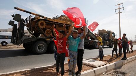 Boys wave Turkish flags as a military convoy drives near the border town of Akcakale in the Turkish province of Sanliurfa near the border of Syria, on Monday. SYRIA-SECURITY/TURKEY-USA