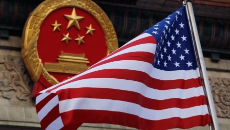 In this Nov. 9, 2017, file photo, an American flag is flown next to the Chinese national emblem during a welcome ceremony for visiting U.S. President Donald Trump outside the Great Hall of the People in Beijing. The State Department said an email notice Wednesday, May 23, 2018, that a U.S. government employee in southern China reported abnormal sensations of sound and pressure, recalling similar experiences among American diplomats in Cuba who later fell ill. China U.S. flag