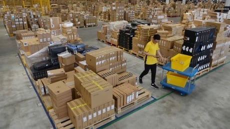 A worker passes by goods piled up at a warehouse in Nanjing in east China's Jiangsu province in June. China's economic growth slowed to its lowest level in decades amid a tariff war with Washington. China Economy