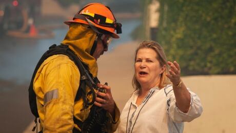 A Palisades resident talks with a firefighter before evacuating her home as a wildfire erupts in the Pacific Palisades area of Los Angeles, Monday, Oct. 21, 2019. California Wildfires