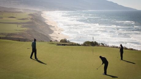 A trio of golfers putts on the 17th green at the Cabot Cliffs golf course in Inverness, N.S., which has gained international recognition along with its sister course Cabot Links. Cabot 17th green