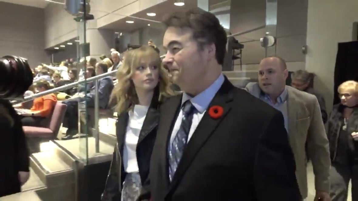 A man with a poppy on his suit walks through Ottawa City Council chambers