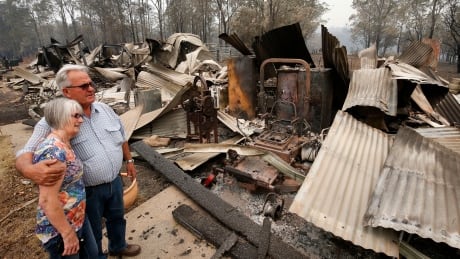 Lyn and Peter Iverson look at the destroyed office and shed on their property following a bushfire at Half Chain Road, Koorainghat, New South Wales state on Mon., Nov. 11, 2019. Australia Wildfires