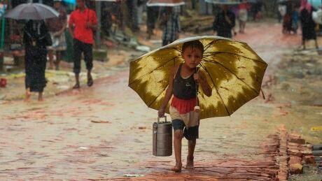 A Rohingya refugee boy shelters under an umbrella as he makes his way during a monsoon rainfall at Kutupalong refugee camp in Ukhia, Bangladesh on Sept. 12. 1167514712
