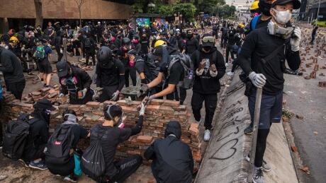Protesters build a wall to block a road at The Hong Kong Polytechnic University, in Hong Kong on November 14, 2019. - Pro-democracy protesters challenging China's rule of Hong Kong on November 14 choked the city for a fourth straight working day, firing arrows at police, barricading roads and disrupting transport links, as schools and businesses closed. 1182240222