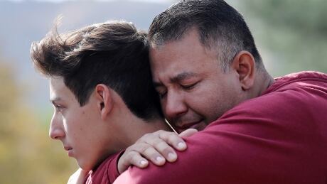 SANTA CLARITA, CALIFORNIA - NOVEMBER 14: Marco Reynoso (R) hugs his son, 11th-grader Dylan Reynoso, after reuniting at a park near Saugus High School after a shooting at the school left two students dead and three wounded on November 14, 2019 in Santa Clarita, California. A suspect in the shooting is being treated at a local hospital for a gunshot wound to the head. (Photo by Mario Tama/Getty Images) 1187686872
