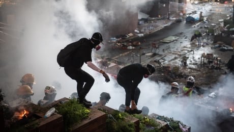 aHONG KONG, CHINA - NOVEMBER 18: Anti-government protesters walk past a fire during clashes with police at Hong Kong Polytechnic University on November 18, 2019 in Hong Kong, China. Anti-government protesters organized a general strike since Monday as demonstrations in Hong Kong stretched into its sixth month with demands for an independent inquiry into police brutality, the retraction of the word "riot" to describe the rallies, and genuine universal suffrage. 1183152867