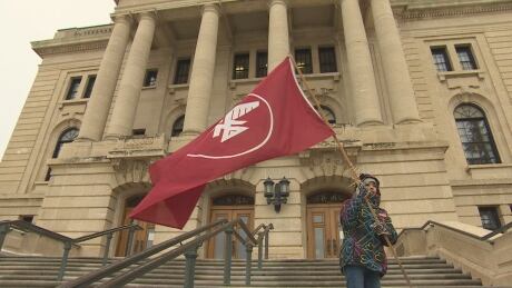 A child waves a flag ahead of a rally calling for an immediate end to coerced sterilization in Canada at the Saskatchewan Legislative Assembly on Nov. 26, 2019. First Nation leaders in Saskatchewan called the forced procedure a "disgusting" act of violence against Indigenous women and families. Coerced sterilization rally